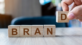 Businessman hand holding wooden cube block with BRAND business word on table background. Marketing, Advertising and Product development concept